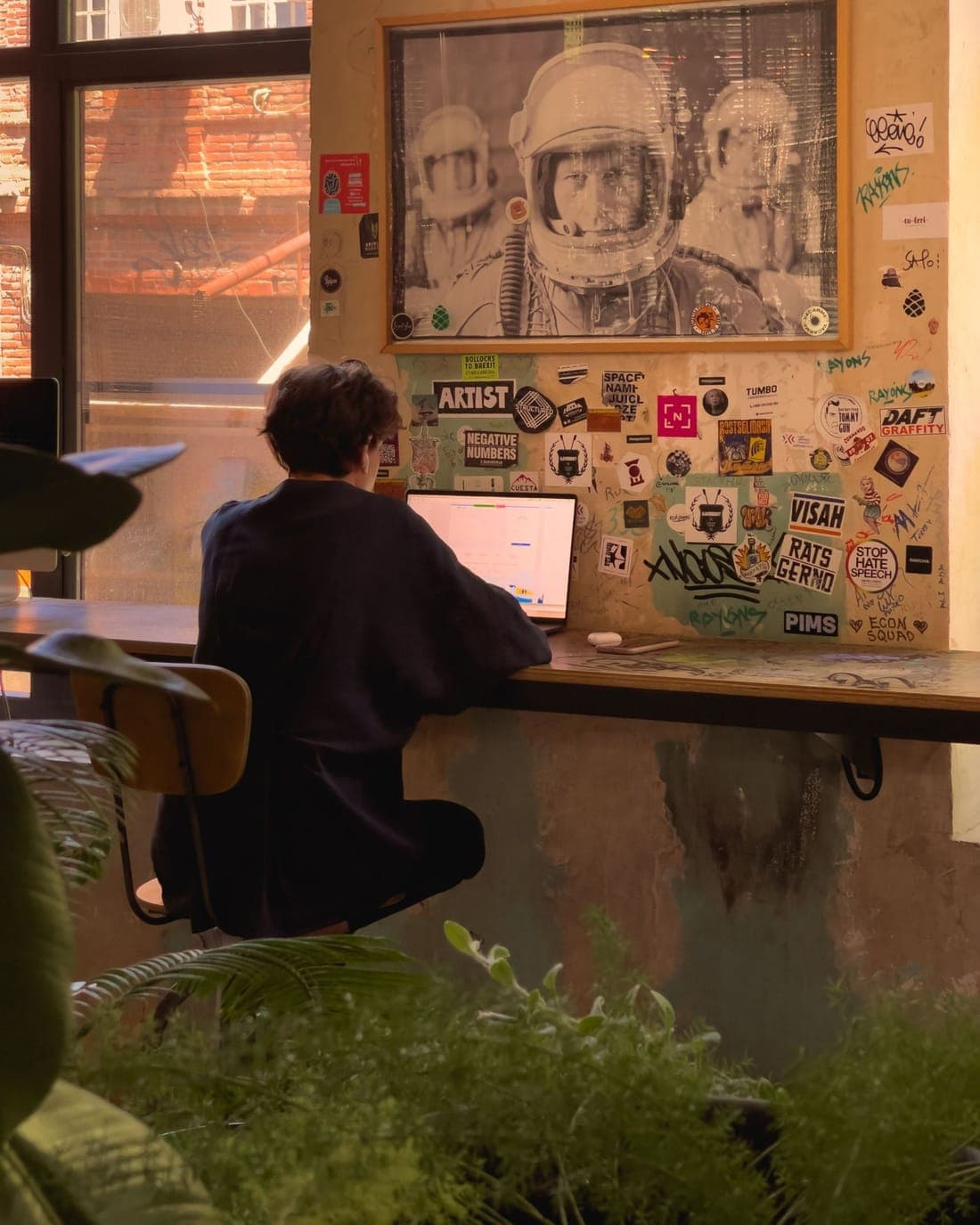 Freelancer aan het werk op een laptop, aan een bar vol stickers